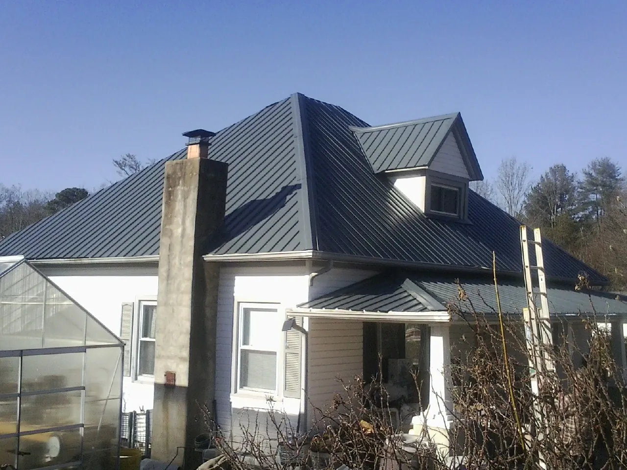 Dark blue standing seam metal roof on a white farmhouse with dormer — Slate & Tile Roof Repair by Roofing Brothers in Hampton Falls