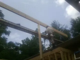 Carpenter setting a ridge beam over a new addition frame — Ice Dam Removal by Roofing Brothers in Hampton Falls