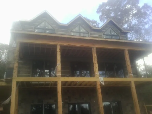 Dormers and porch framing on a large log home under construction — Roof Coating work by our crew in Hampton Falls