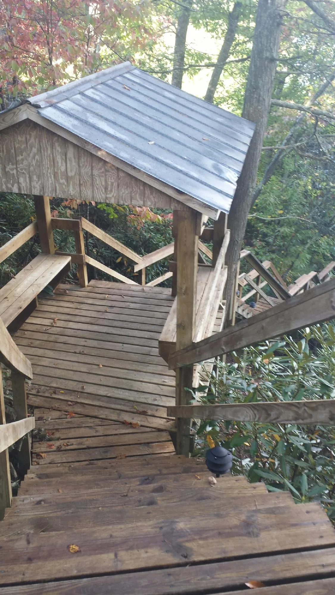 Metal roofed shelter over wooden steps on a wooded walkway — Skylight Repair & Installation work by our crew in Hampton Falls
