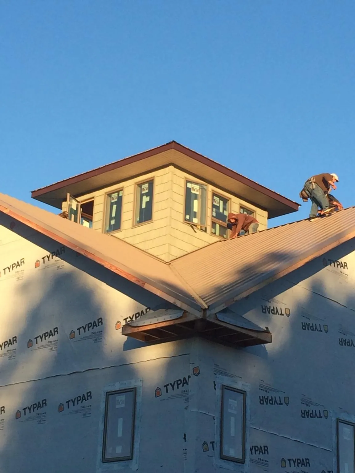 Roofers working around a rooftop cupola on a new metal roof at sunset — Roof Waterproofing in Hampton Falls by Roofing Brothers